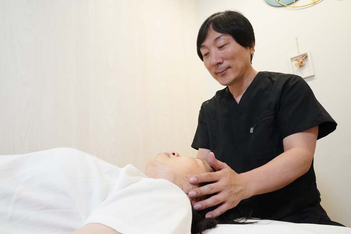 頭部へやさしく触れて体の反応を確認する神経整体の施術風景
